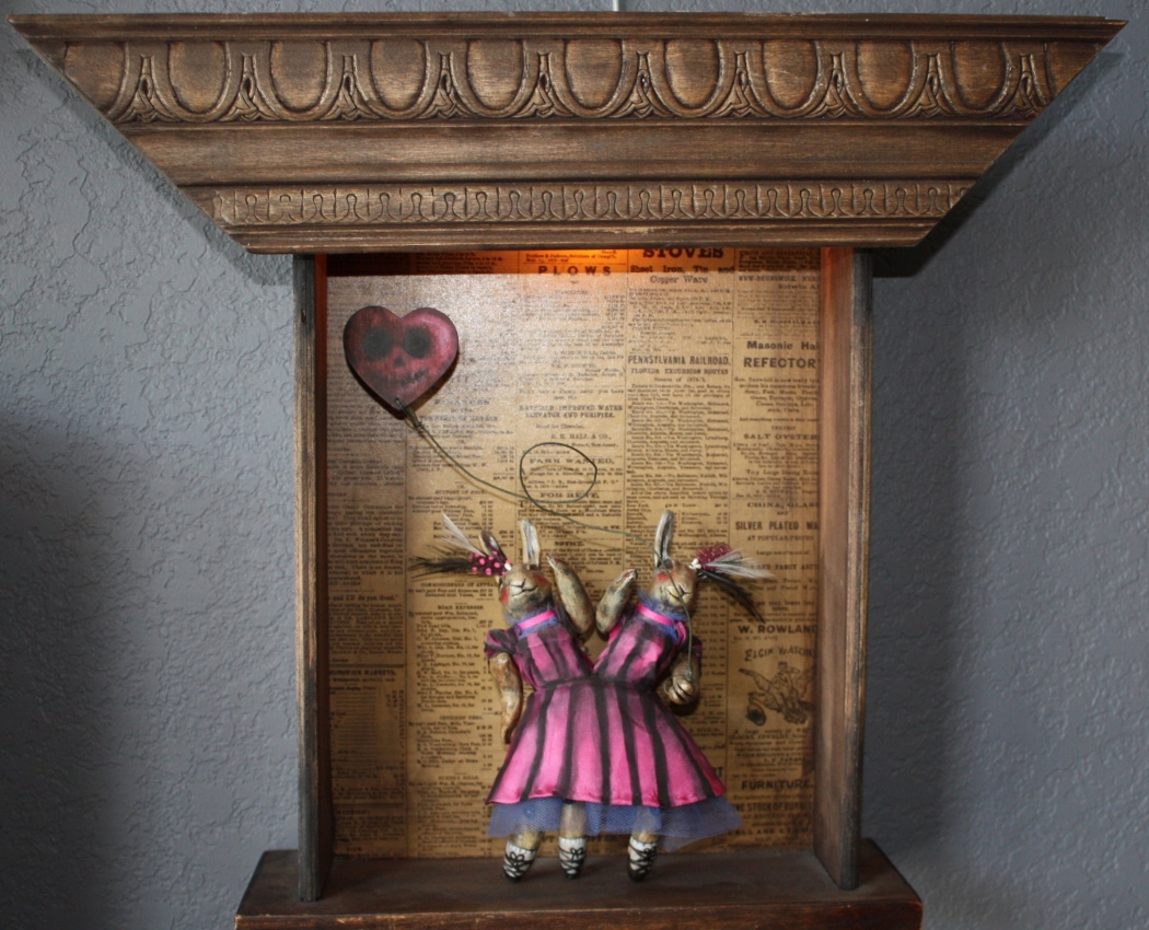 IPHY & OLLY Named after the twins from the book "Geek Love", this piece was also part of the CIrcus Curiosities series. The twins were sculpted from clay and have all moveable parts. Their dress was hand sewn and painted. They are set in a salvaged drawer and illuminated by an electric light.