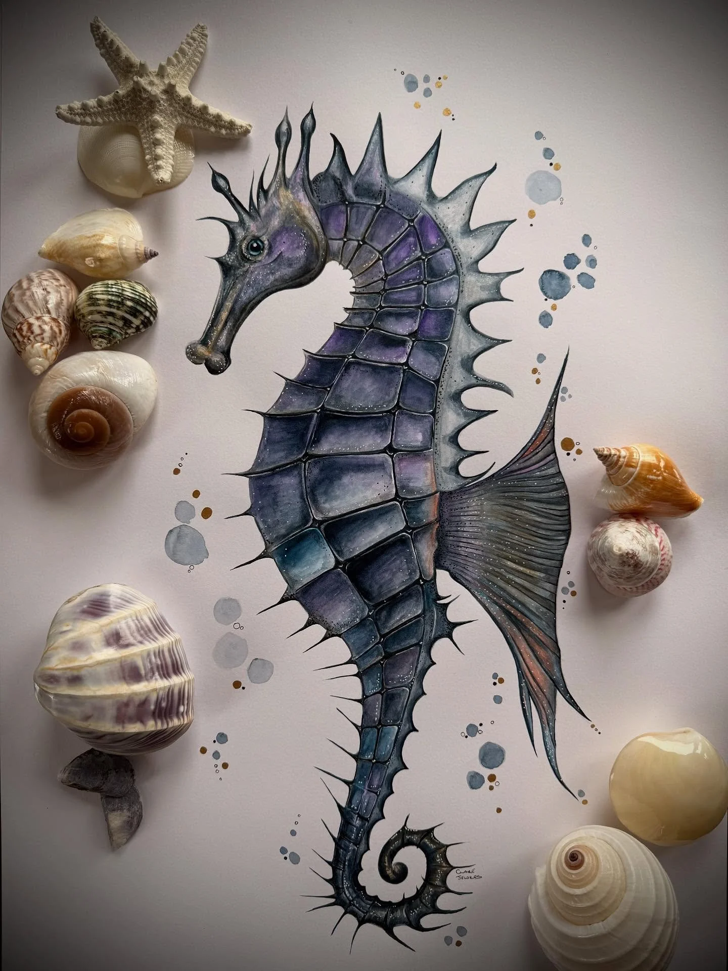 Between coral shadows and moonlit water, the seahorse drifts armoured in beauty, unhurried, untamed. 🌊✨ 
 Each tiny plate painted in layers of gold, violet, indigo and whispering grey, an ocean relic with a heartbeat of calm.

&lsquo;FROM OUR SEA&rs