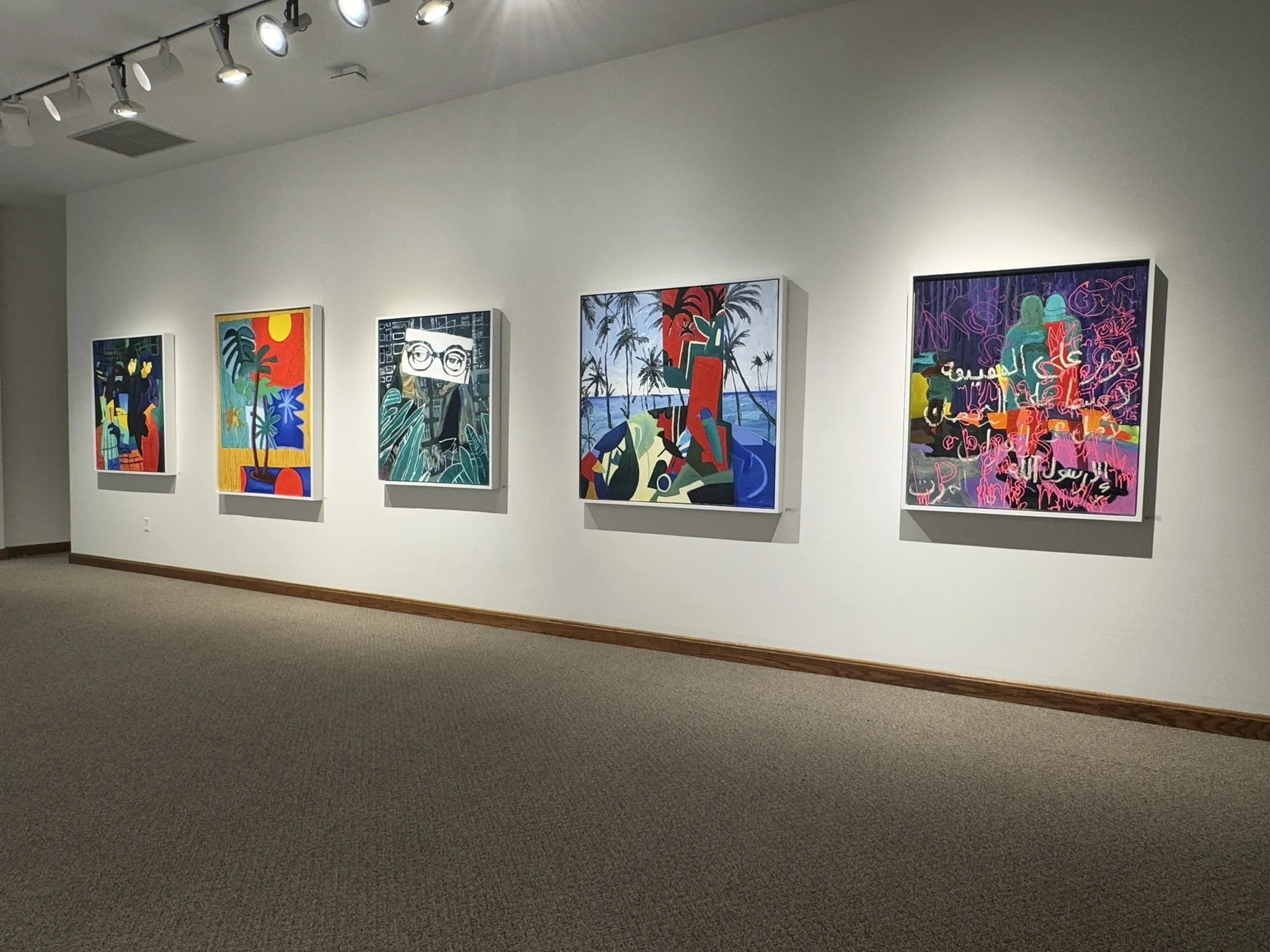 Five colorful paintings with abstract and modern art styles are displayed on a white gallery wall, illuminated by overhead lights.