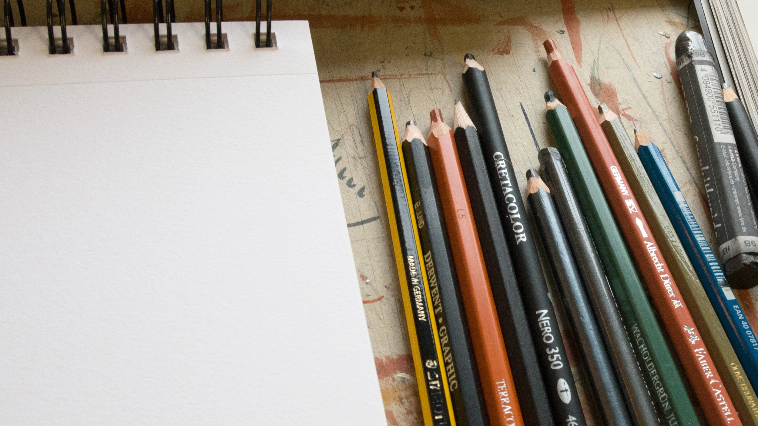 Sketchbook and colored pencils on a table.