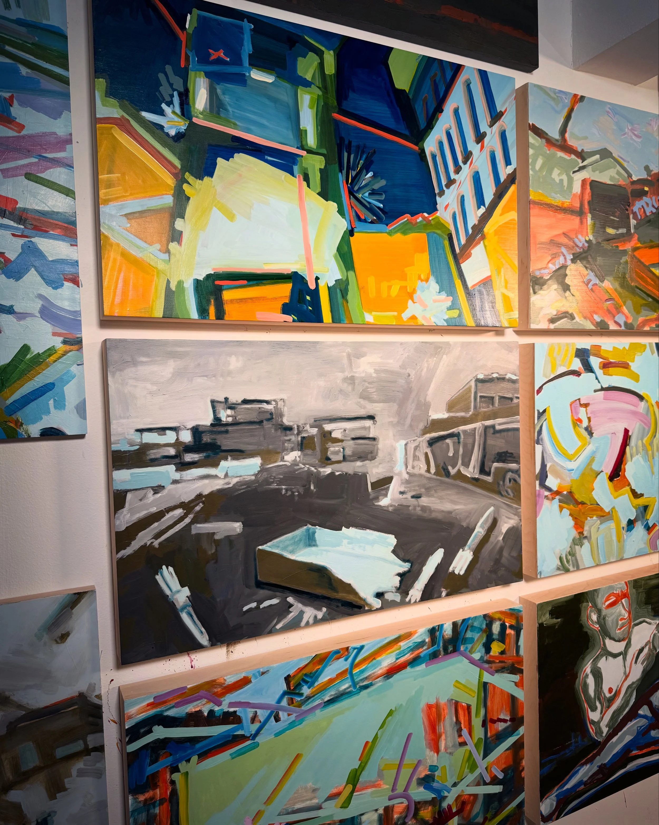 A collection of abstract paintings on a wall, featuring vibrant colors and geometric shapes. Each artwork displays a unique style with bold lines and dynamic brush strokes.