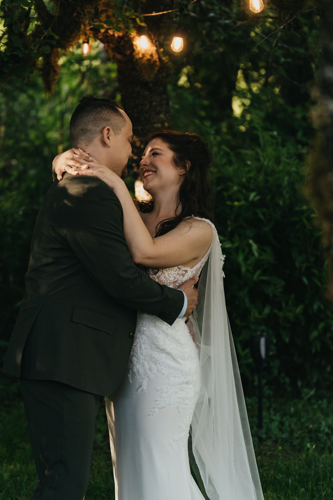 bride and groom cuddling under lights