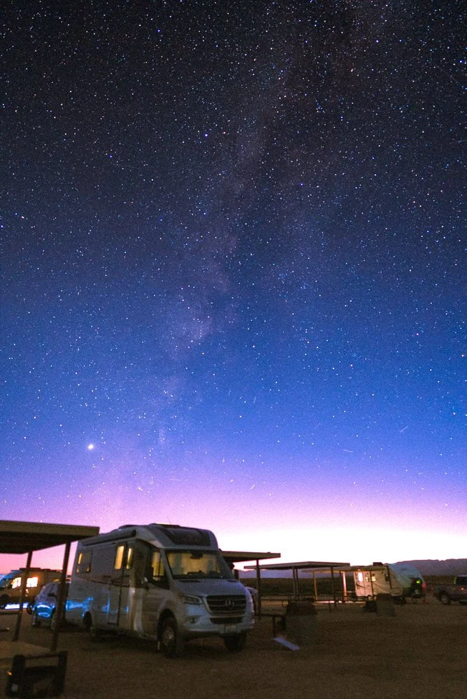 an LTV RV sits in a campsite with the milkyway behind it in the sky
