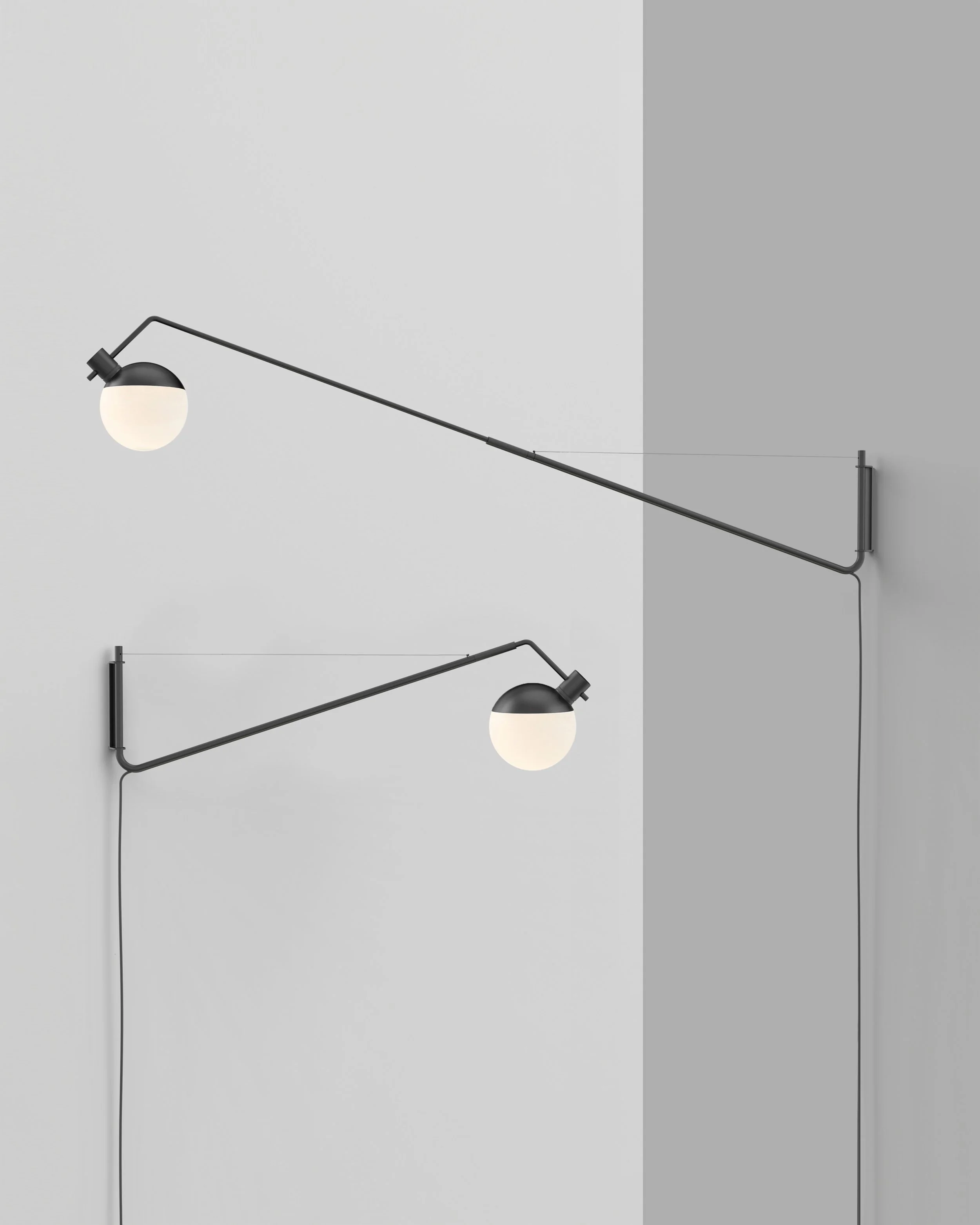 Zwei moderne schwarze Wandleuchten mit weißen kugelförmigen Lampenschirmen an einer weißen Wand von der Marke „grupa“