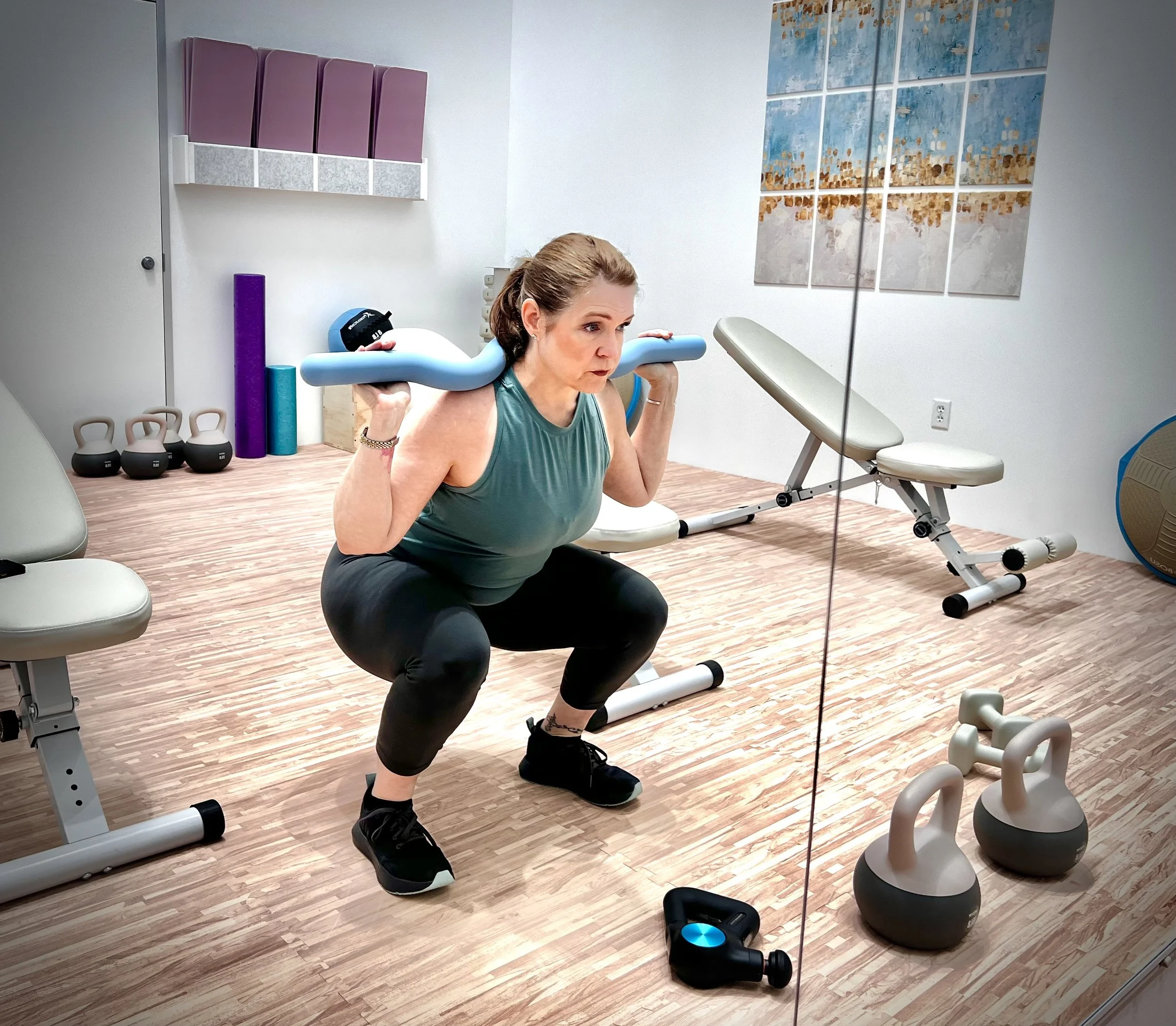 Female performing a barbell squat in a gym with nuetral color palette