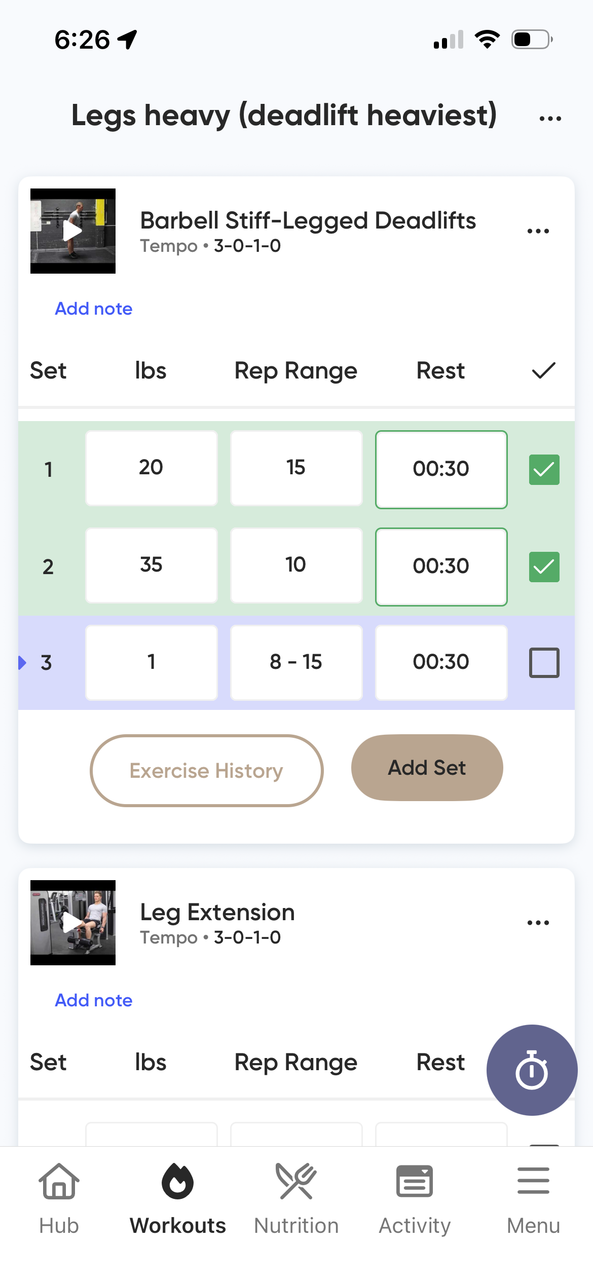Workout plan on smartphone screen for heavy legs and leg extension exercises, including sets, reps, and rest timings.