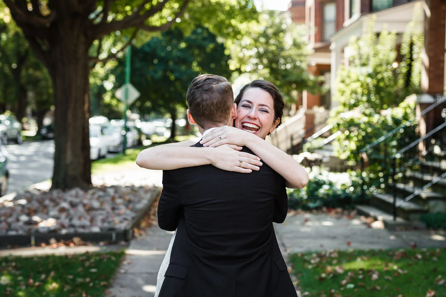 bride and groom embracing on the sidewalk in front of their Roscoe village apartment in Chicago