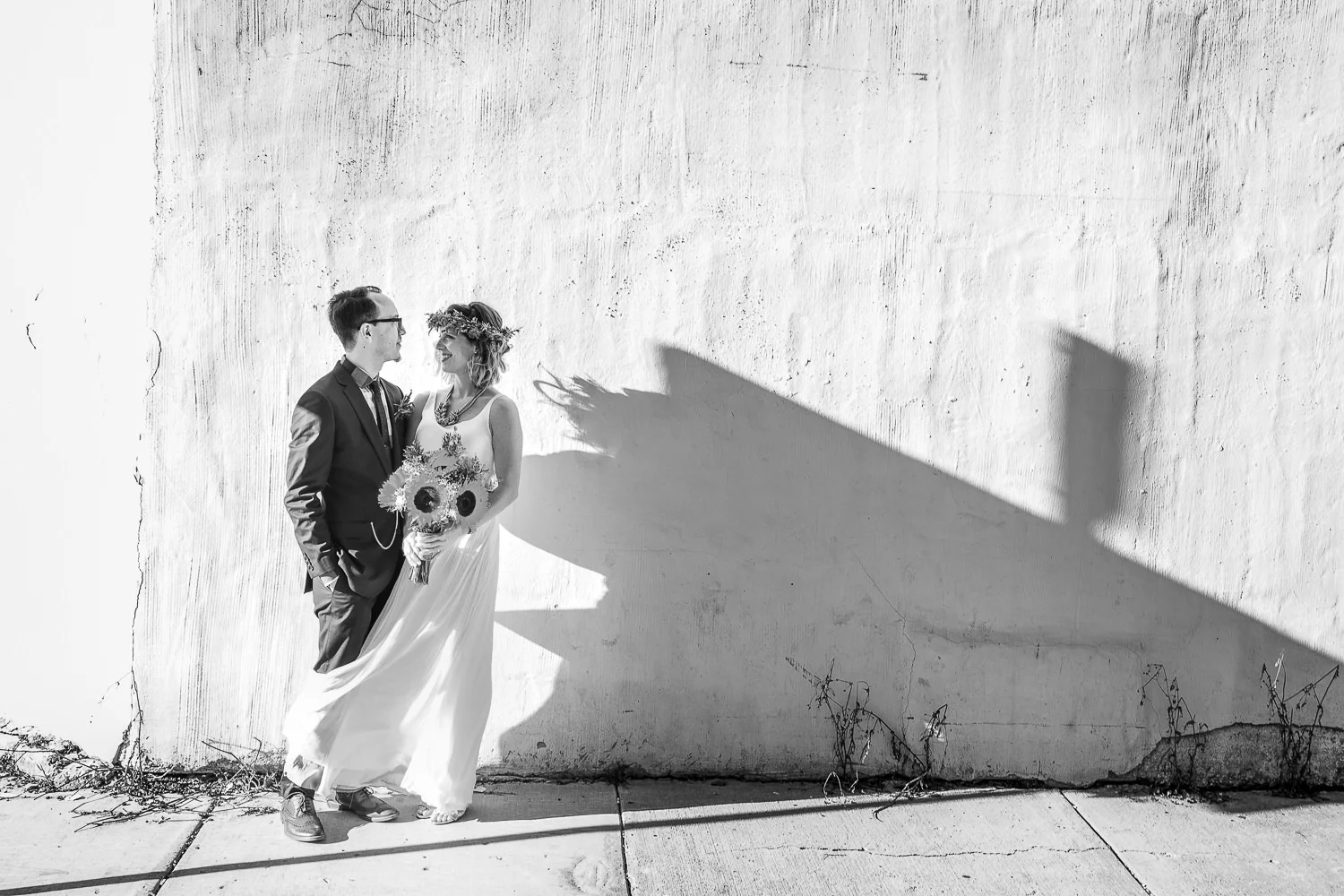 black and white photograph of a bride and groom standing in front of a stark wall in Logan Square