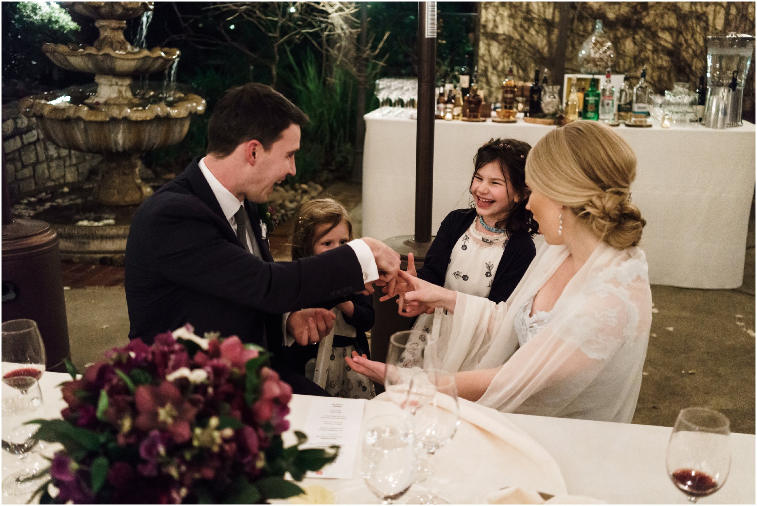 bride and groom talking to flower girls during dinner