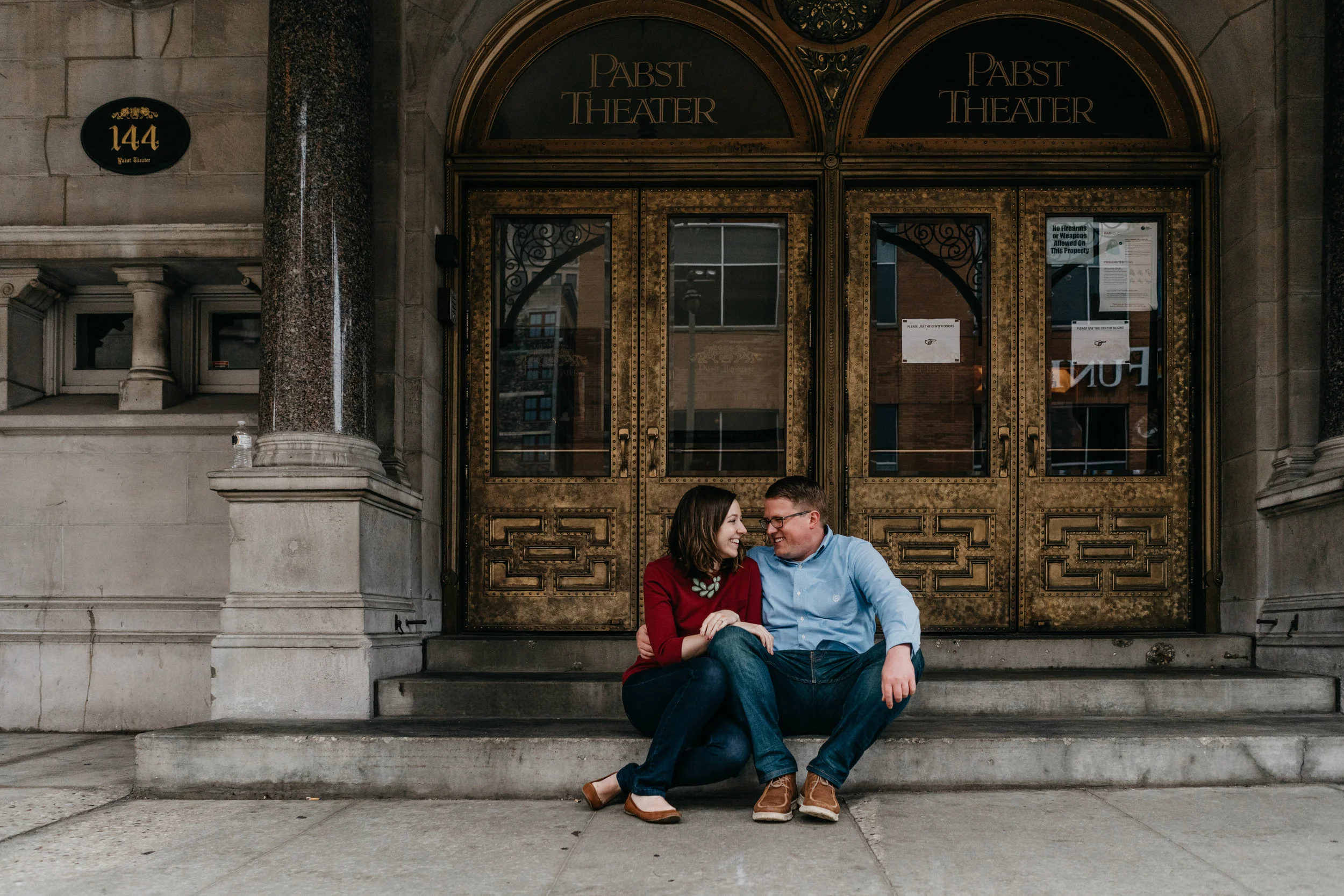 engaged couple sitting in front of Milwaukee’s Pabst Theater