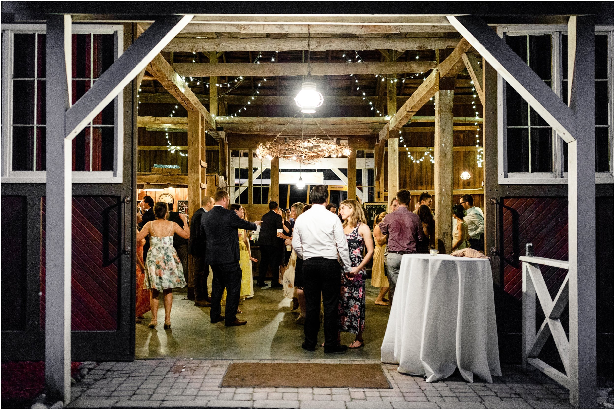 wedding guests dancing during reception in a barn