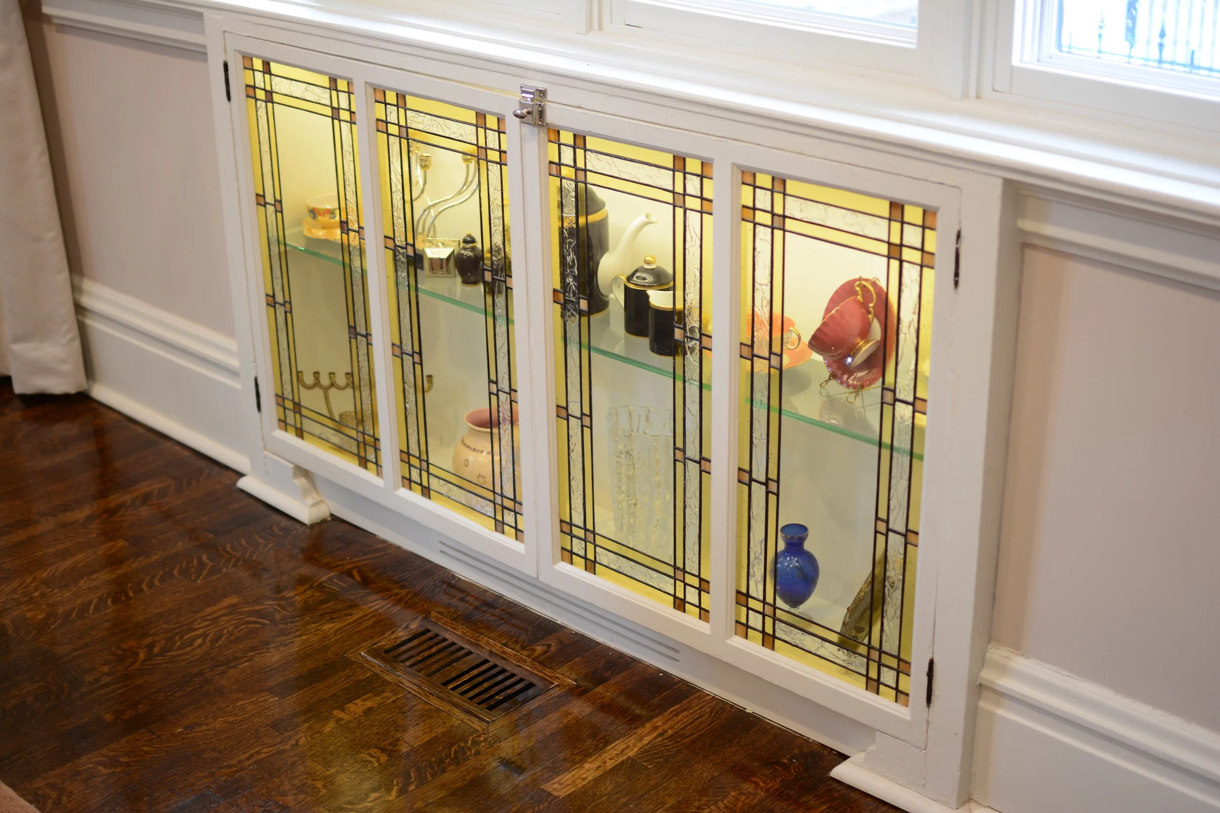 Converting a 100 year old radiator cove into a stained-glass lit cabinet enhances warmth and impact.