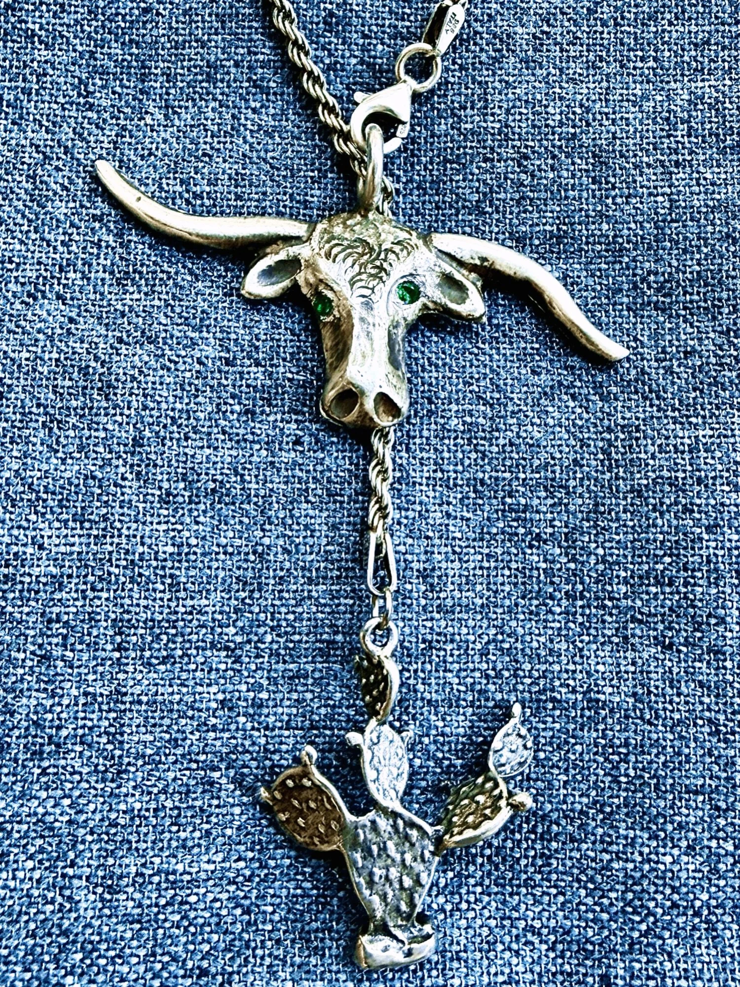 Antique sterling lariat necklace with longhorn w emerald eyes and prickly pear cactus charm 
Available here: https://theoldspanishtrading.com/silver-buckles-and-conchos/antique-sterling-lariat-necklace-with-longhorn-w-emerald-eyes-and-prickly-pear-ca