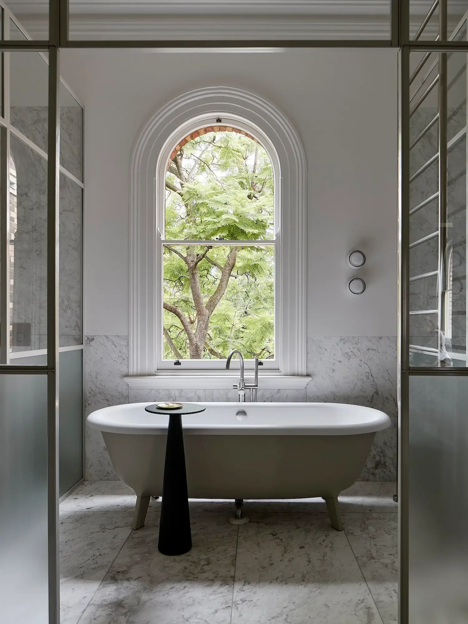 Inspiration image of clawfoot tub in front of an arched window, design by Hecker Guthrie