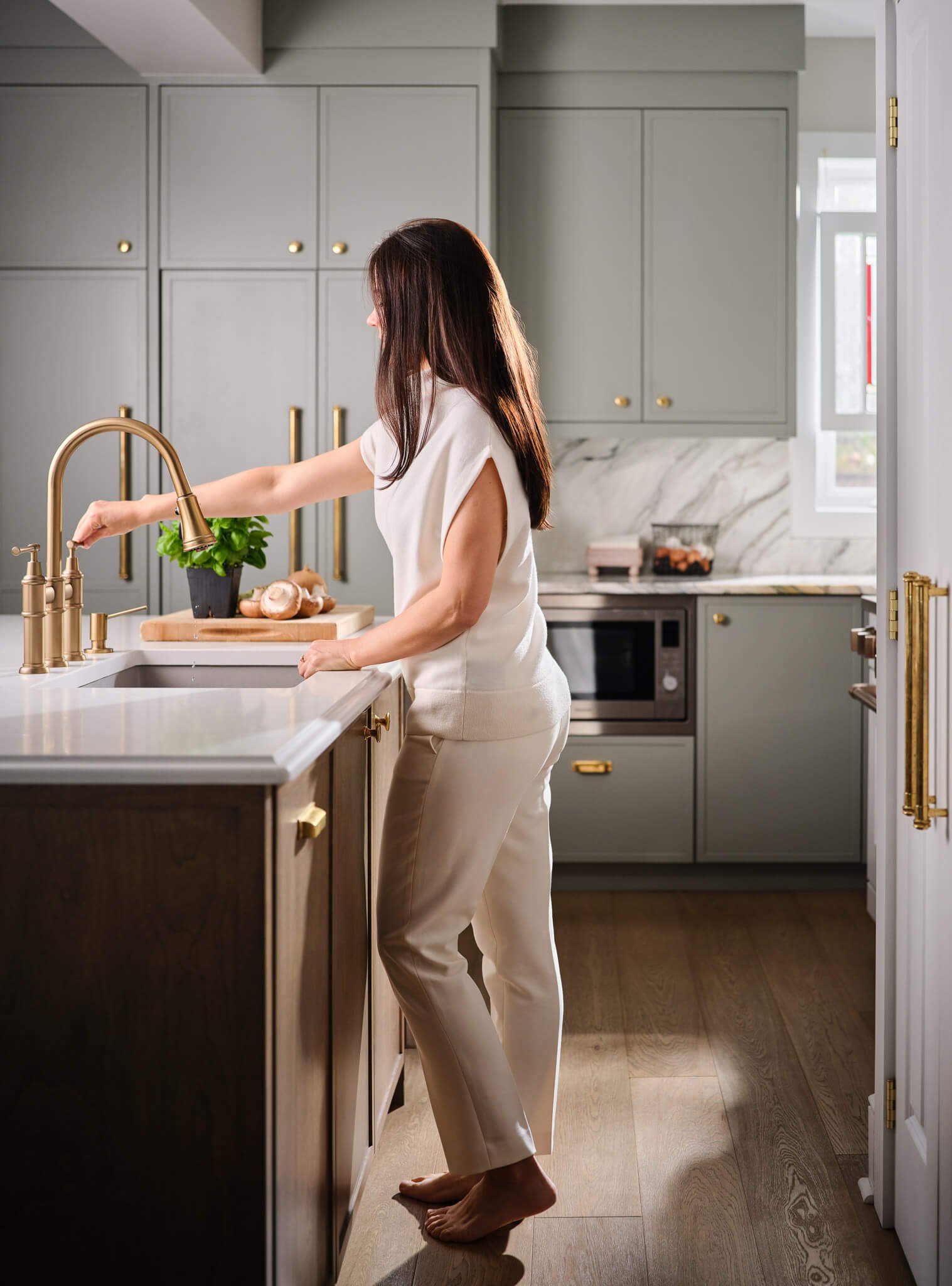 Marina Medina, Vancouver interior designer, standing in a bright transitional kitchen.
