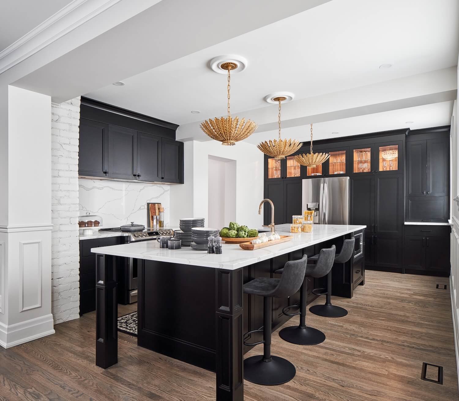 Black transitional kitchen with white countertops and glamorous brass pendants.