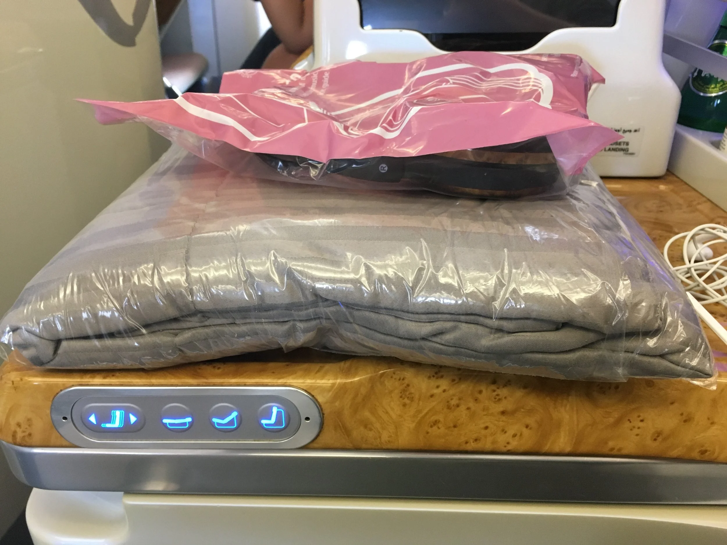 The comfy sheet and noise cancelling headphones atop the side table. You can also see the manual seat controls here.