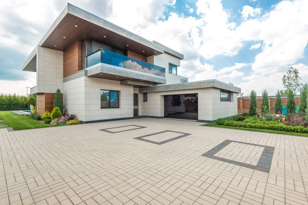 Modern two-story home with a spacious light-colored paver driveway featuring geometric patterns