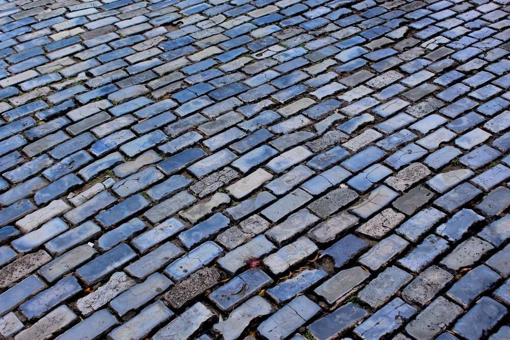 A cobblestone street featuring blue tiles interspersed among the stones
