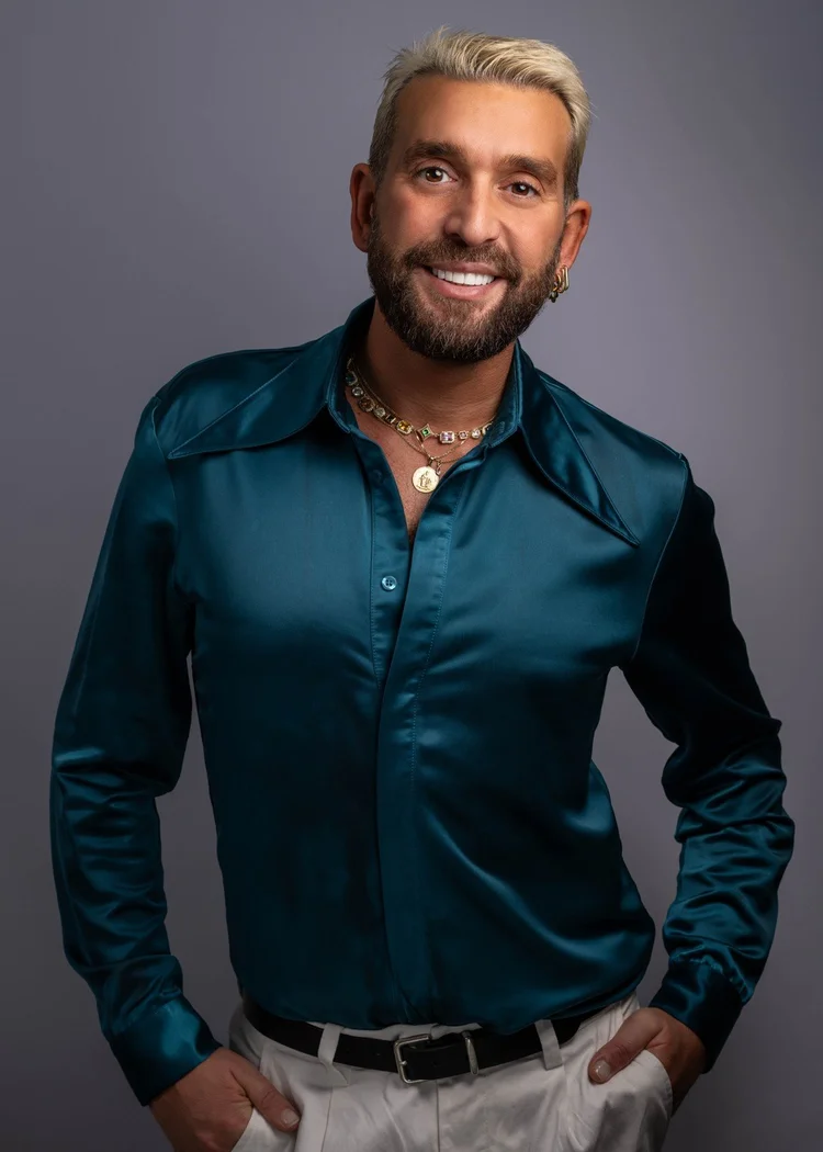 George Katsaros salon team portrait in a teal shirt against a grey background