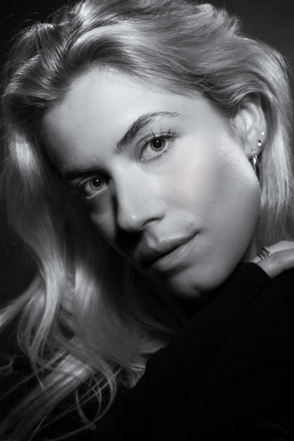 Close-up black-and-white portrait of a woman with swept-back hair and a direct gaze.