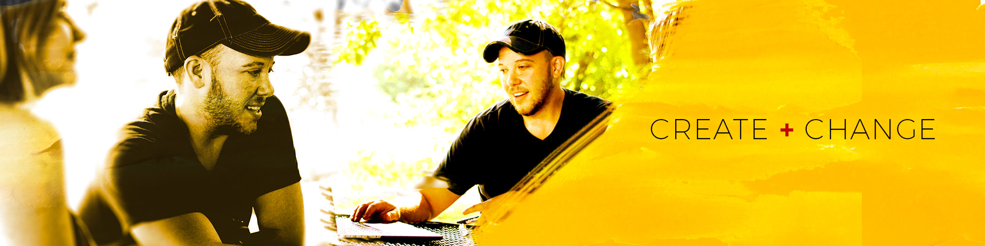 A creative man sitting outdoors at a table, engaged in a conversation, with trees and sunlight in the background and the text "Create + Change" on a yellow painted section to the right.