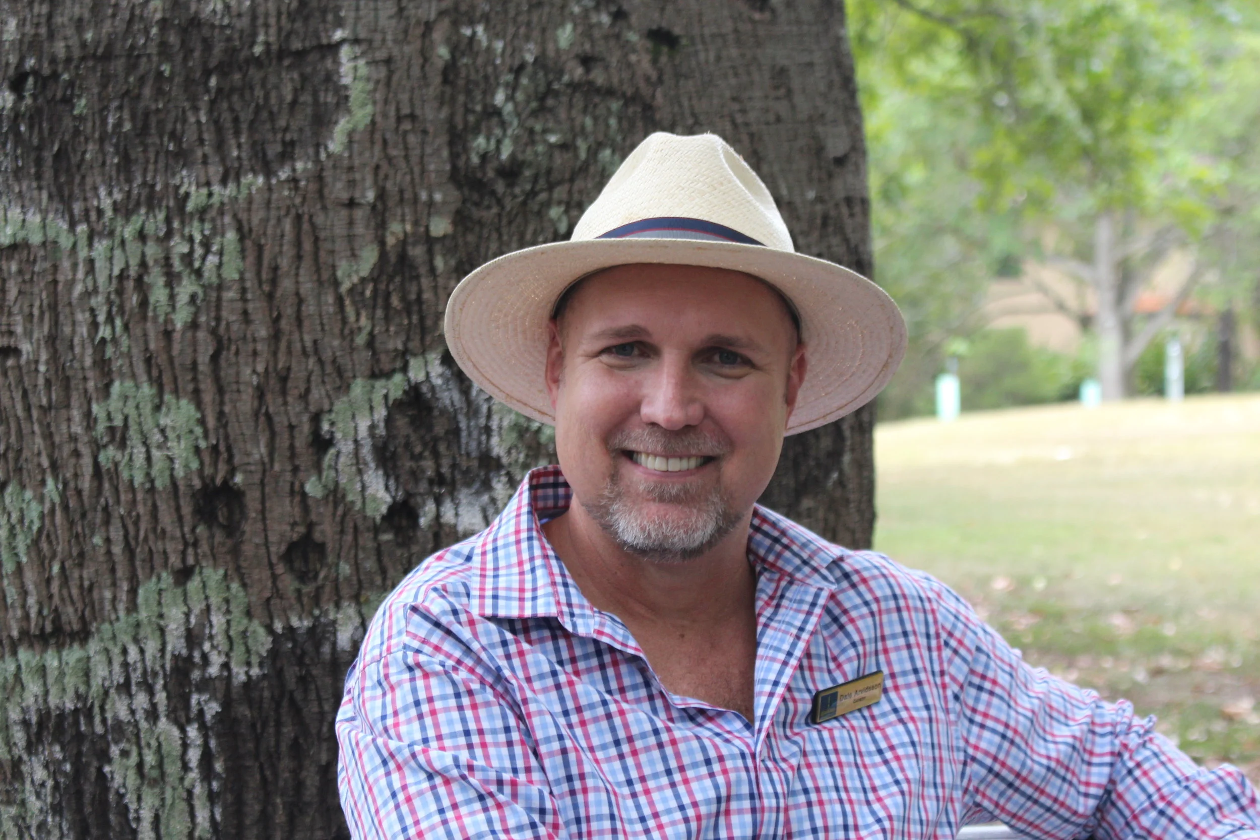 Dale Arvidsson, curator of Brisbane’s Botanic Gardens, sitting in front of Brachychiton rupestris , the Queensland bottle tree.