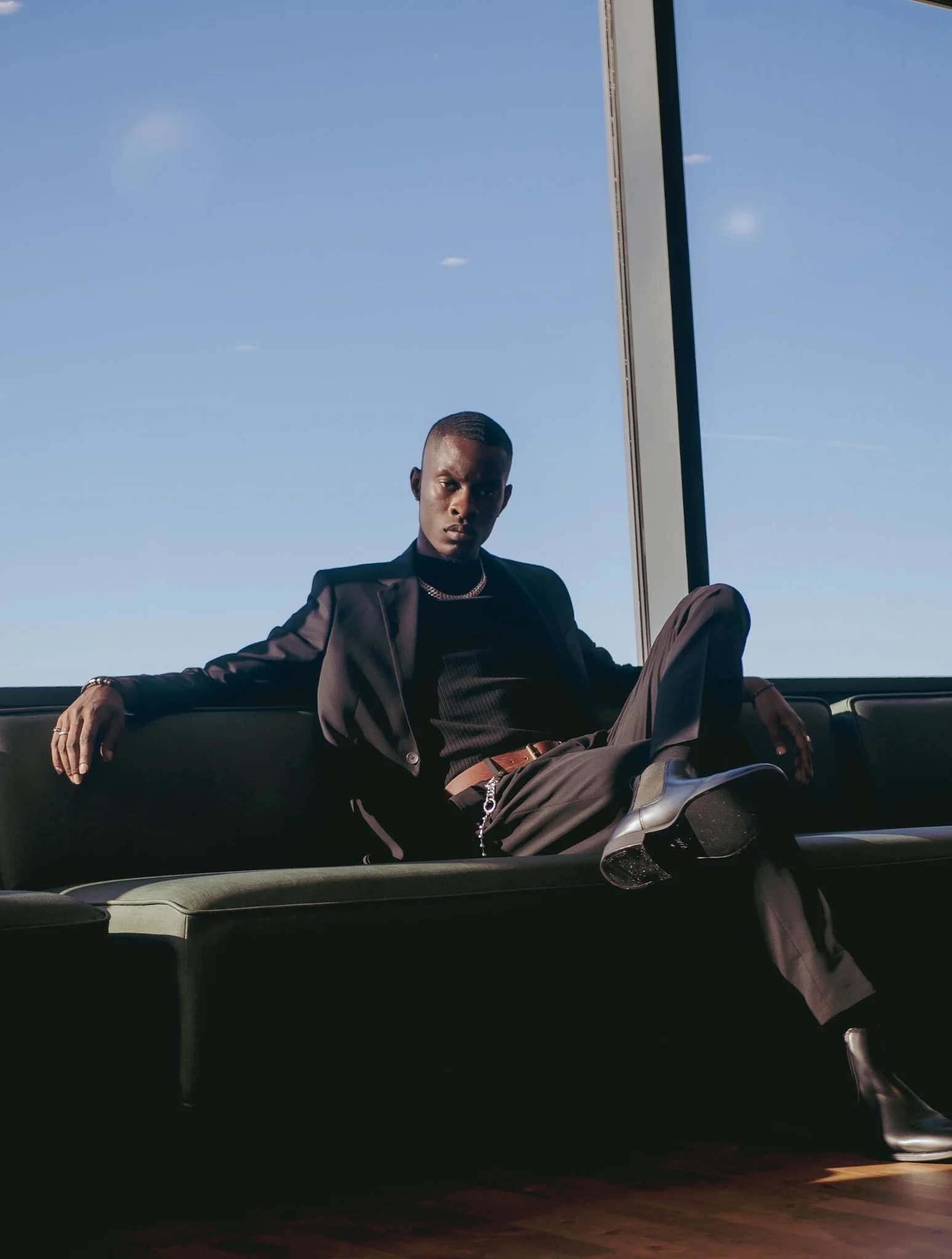 Model reclining in a dark suit against a blue sky for Ralph Lauren Fragrances. Photography by Yonathan Mesfun.