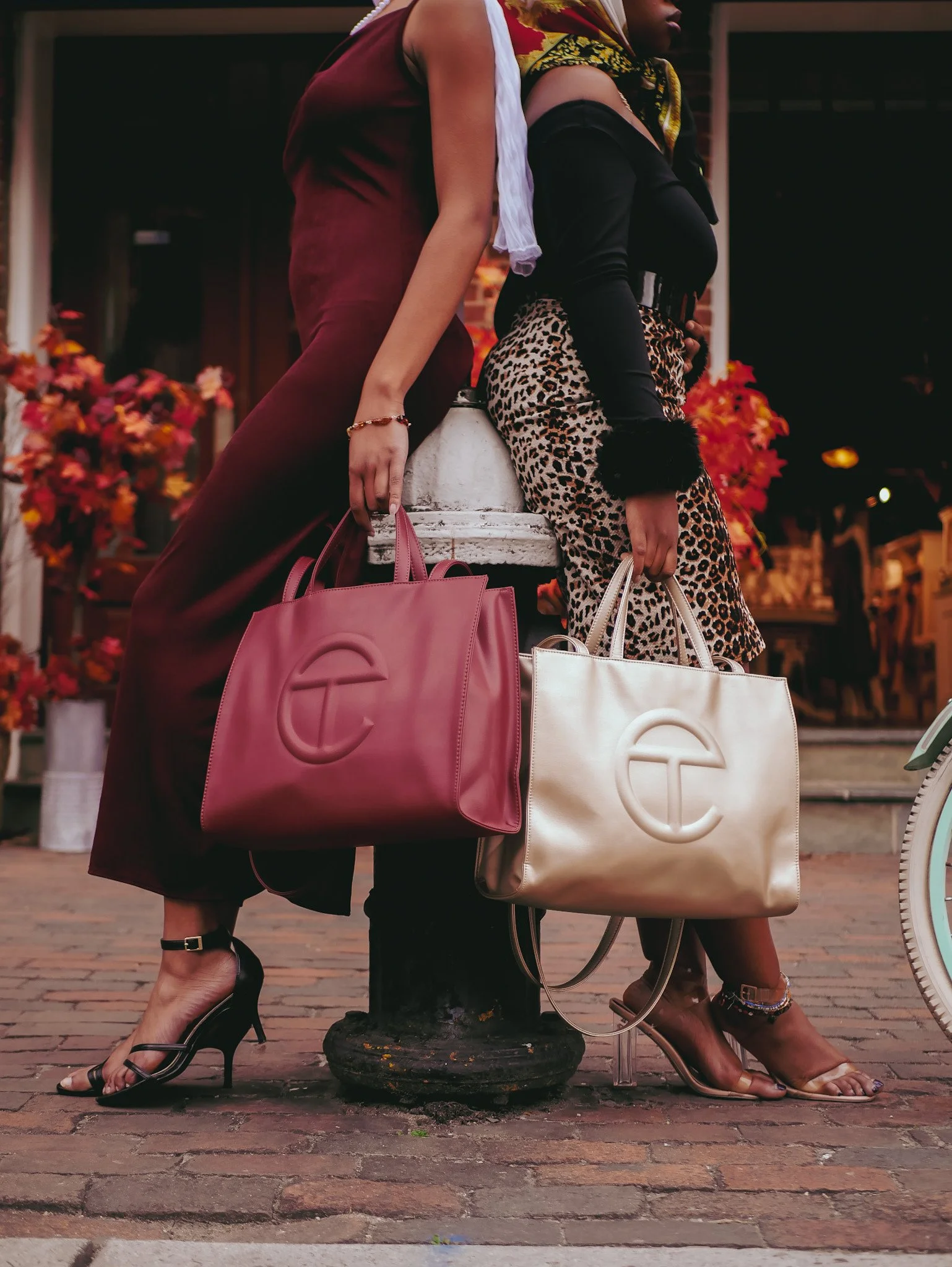 Two models carrying burgundy and cream Telfar bags beside a streetlamp. Photography by Yonathan Mesfun.