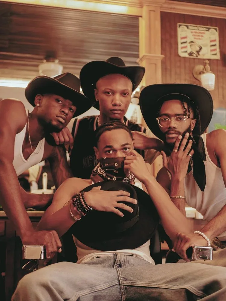 Four models in western hats and layered jewelry gather inside a wood-paneled room in Bad Bandits. Photography by Yonathan Mesfun.