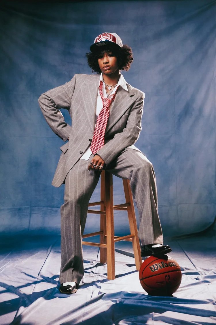 Model in an oversized gray suit and bucket hat poses with a basketball beside a stool in Draft Day. Photography by Yonathan Mesfun.