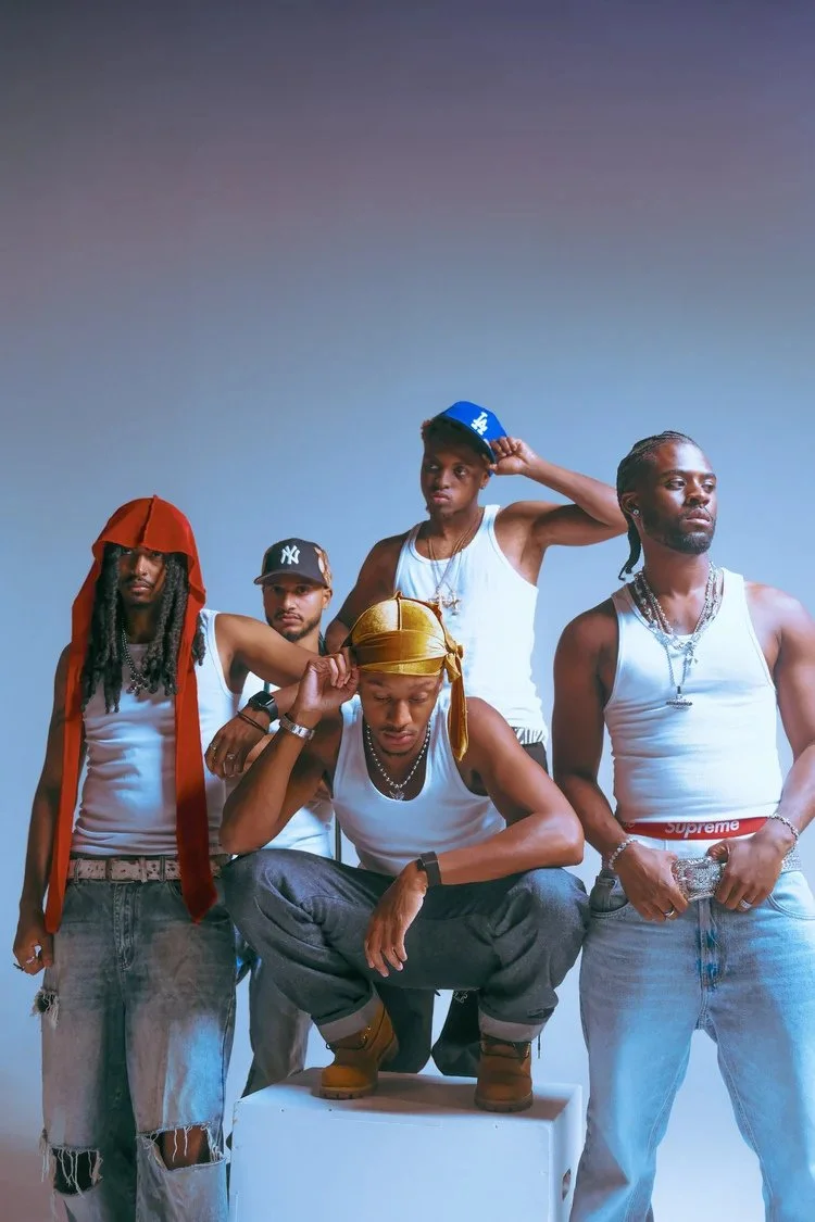 Five models in denim, white tank tops and caps gather for a studio portrait in Denim Boyz. Photography by Yonathan Mesfun.