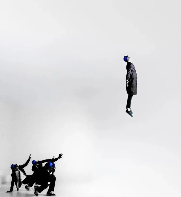 A suited figure appears suspended above three reaching models in Dodger Blue. Photography by Yonathan Mesfun.