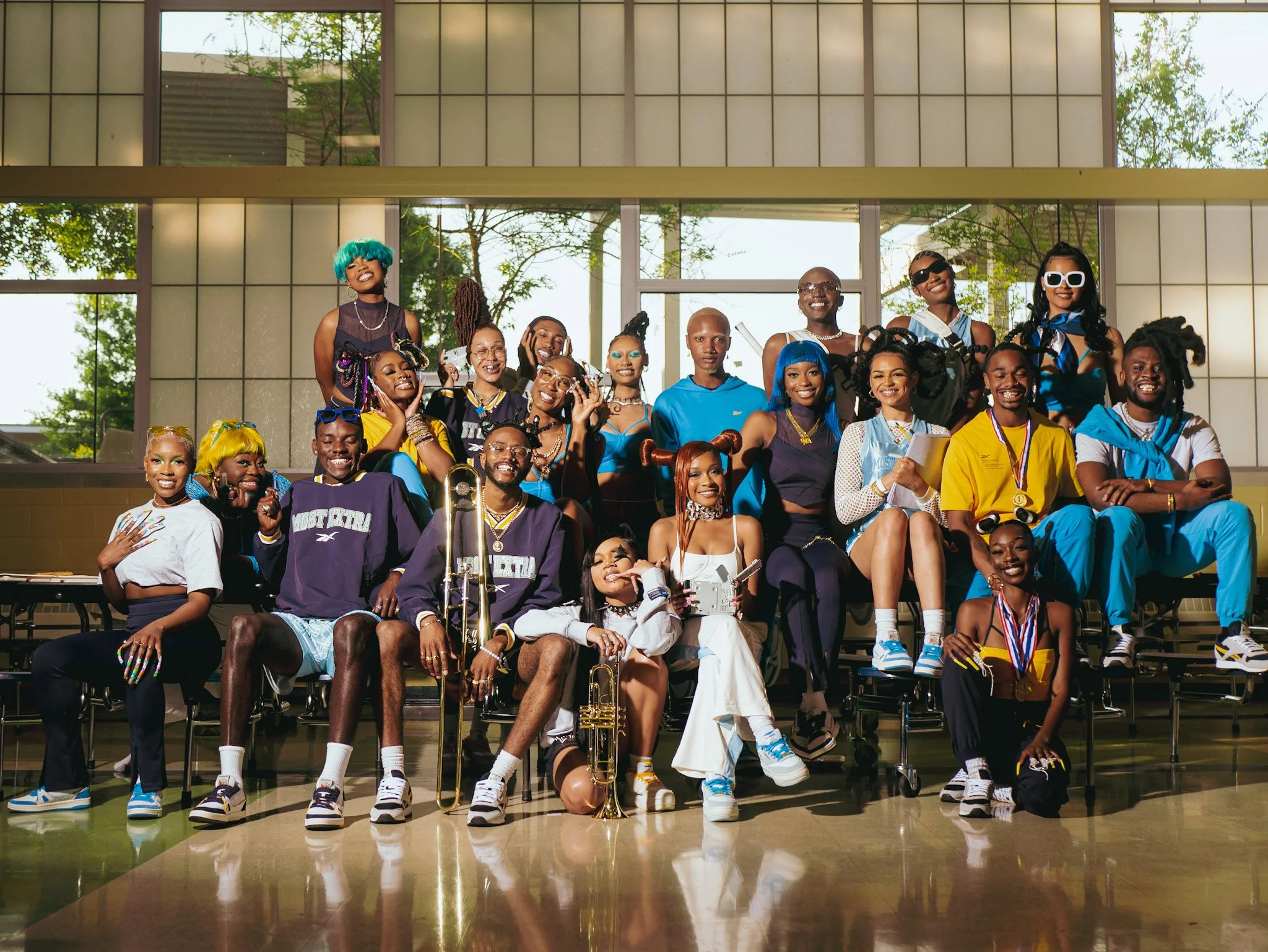Wide group portrait of the Reebok cast on gym bleachers. Photography by Yonathan Mesfun.