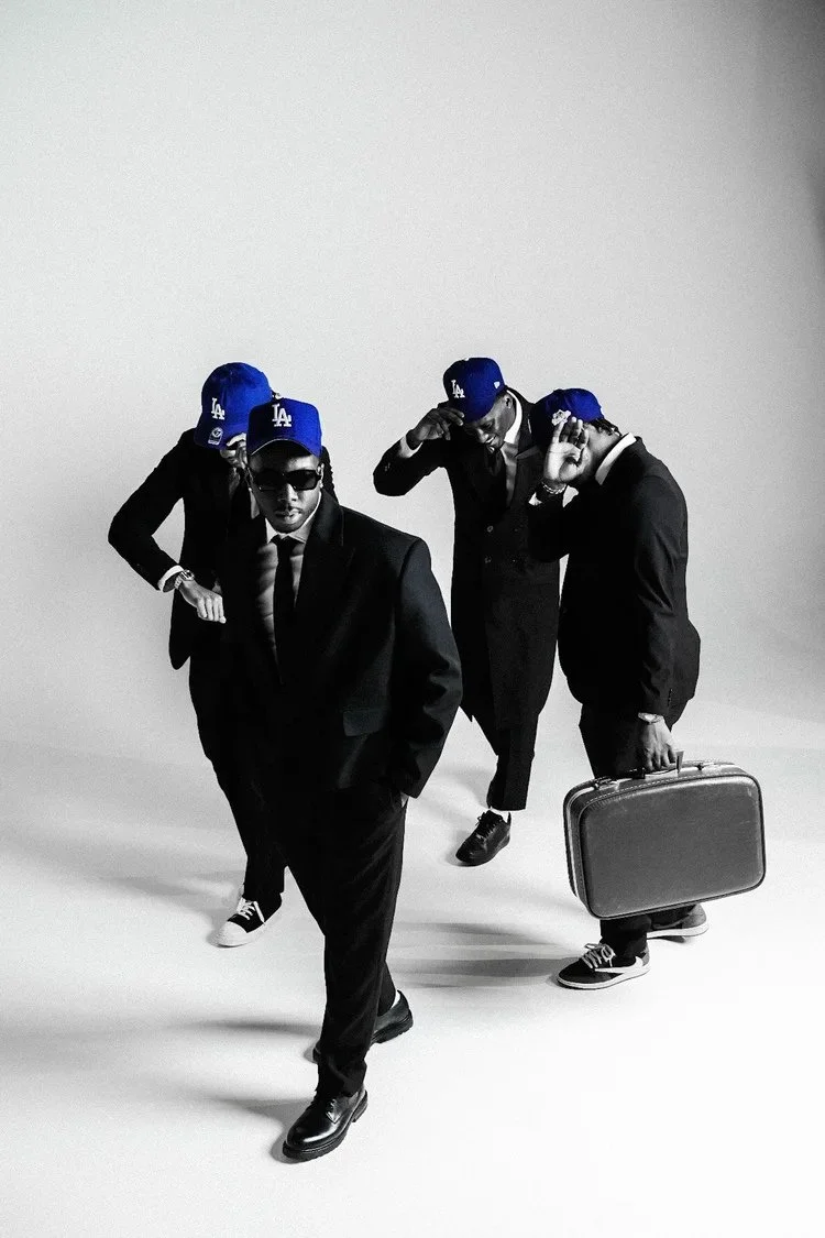 Suited models in blue caps stride toward the camera with a briefcase in Dodger Blue. Photography by Yonathan Mesfun.