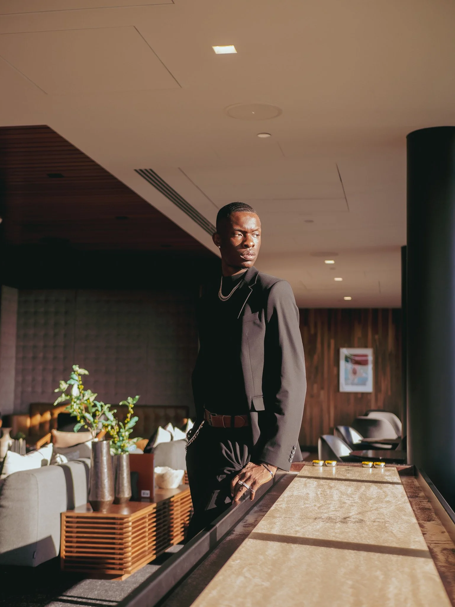 Model in a dark suit leaning against a sunlit bar for Ralph Lauren Fragrances. Photography by Yonathan Mesfun.