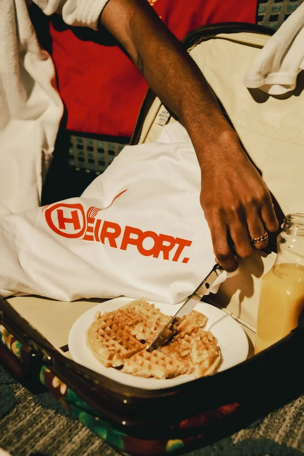 Breakfast tray with waffles beside a white Heirport shirt in a bedroom. Photography by Yonathan Mesfun.