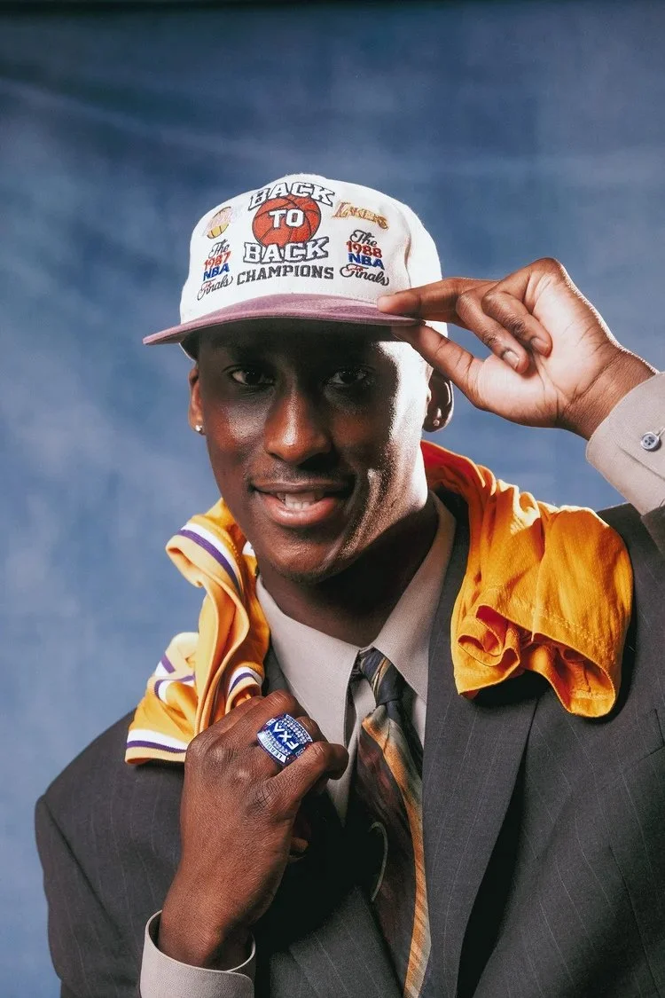 Model in a suit and white cap drapes a yellow basketball jersey over one shoulder in Draft Day. Photography by Yonathan Mesfun.