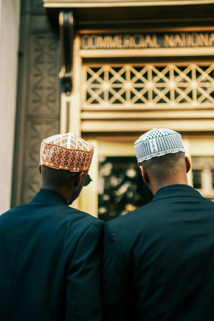 Two men in patterned caps face an ornate doorway in A Collected Culture Pt.2. Photography by Yonathan Mesfun.