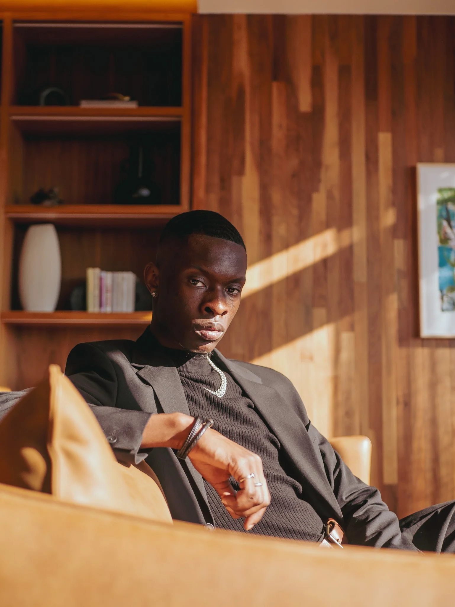 Seated portrait of a model in a dark suit against warm wood and sunlight for Ralph Lauren Fragrances. Photography by Yonathan Mesfun.