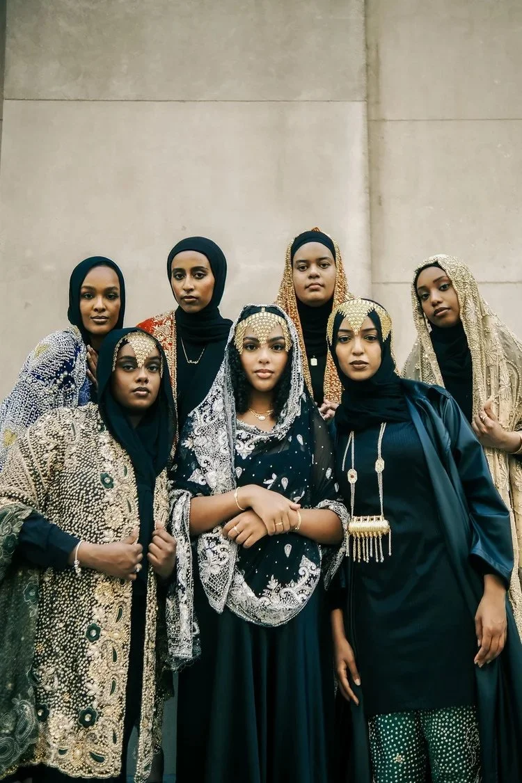 Group portrait of women in dark garments and ornate shawls in A Collected Culture Pt.2. Photography by Yonathan Mesfun.
