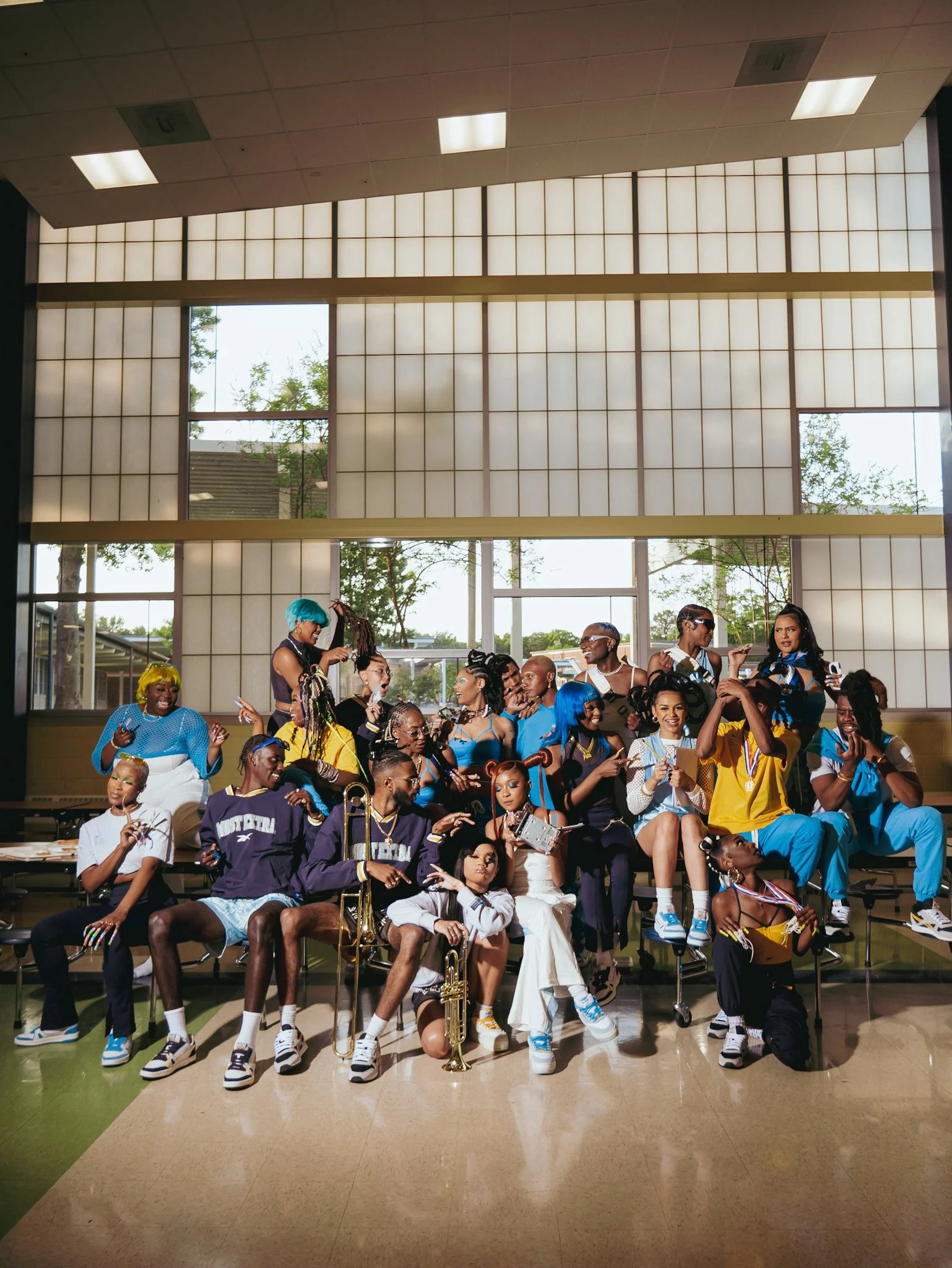 Reebok cast posing together on gym bleachers beneath tall windows. Photography by Yonathan Mesfun.