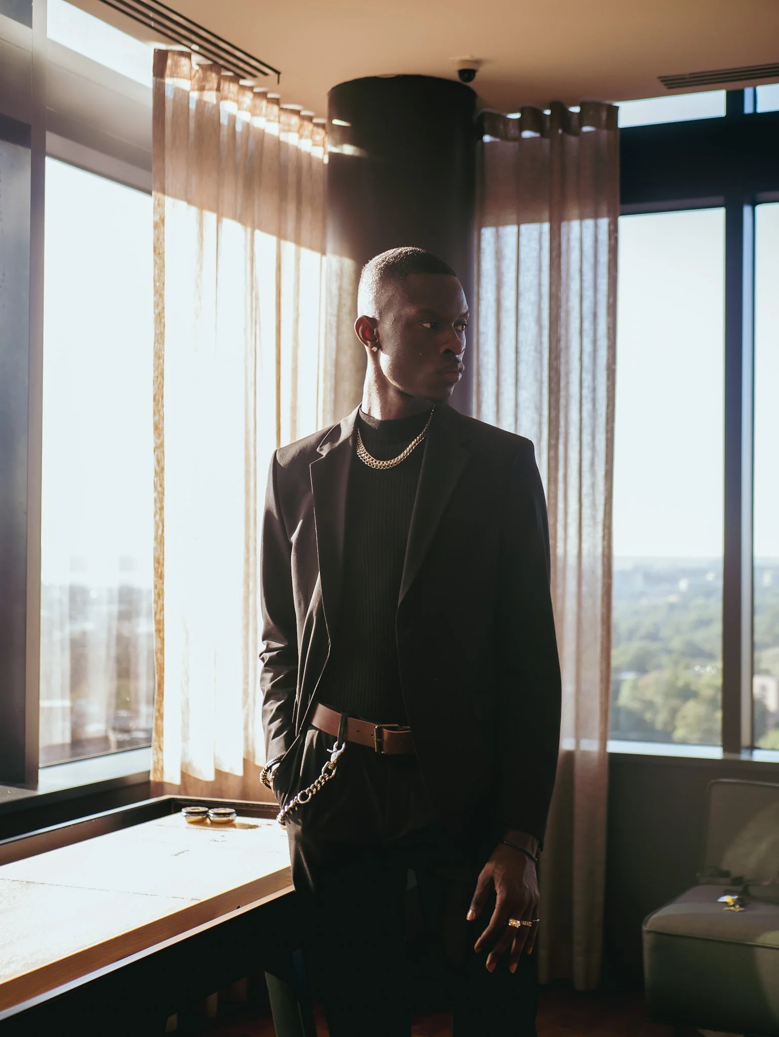 Model in a dark suit beside sunlit windows for Ralph Lauren Fragrances. Photography by Yonathan Mesfun.
