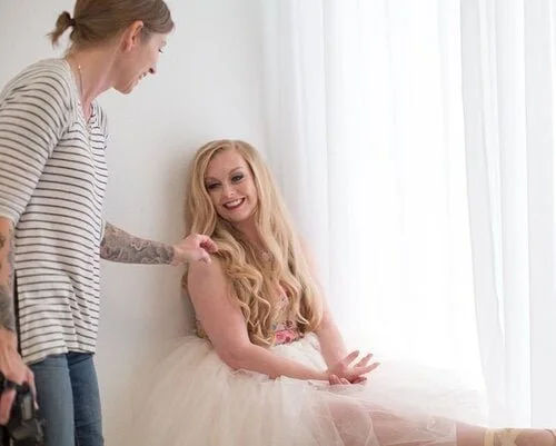 photographer giving direction and adjusting hair for portrait of female ballerina in studio / Photo by Erin Valkner Photography of New Braunfels, Texas. See more at www.erinvalknerphotography.com/blog