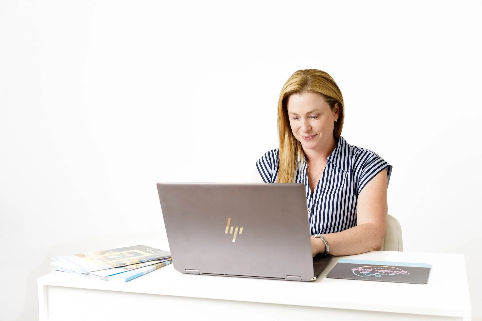branding photos of woman working at laptop at desk with white background in studio / Photo by Erin Valkner Photography of New Braunfels, Texas. See more at www.erinvalknerphotography.com/blog