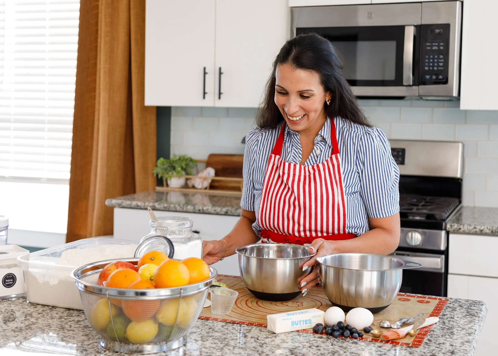 Branding photo of woman in kitchen surrounded by baking supplies looking down and smiling / Photo by Erin Valkner Photography of New Braunfels, Texas. See more at www.erinvalknerphotography.com/blog