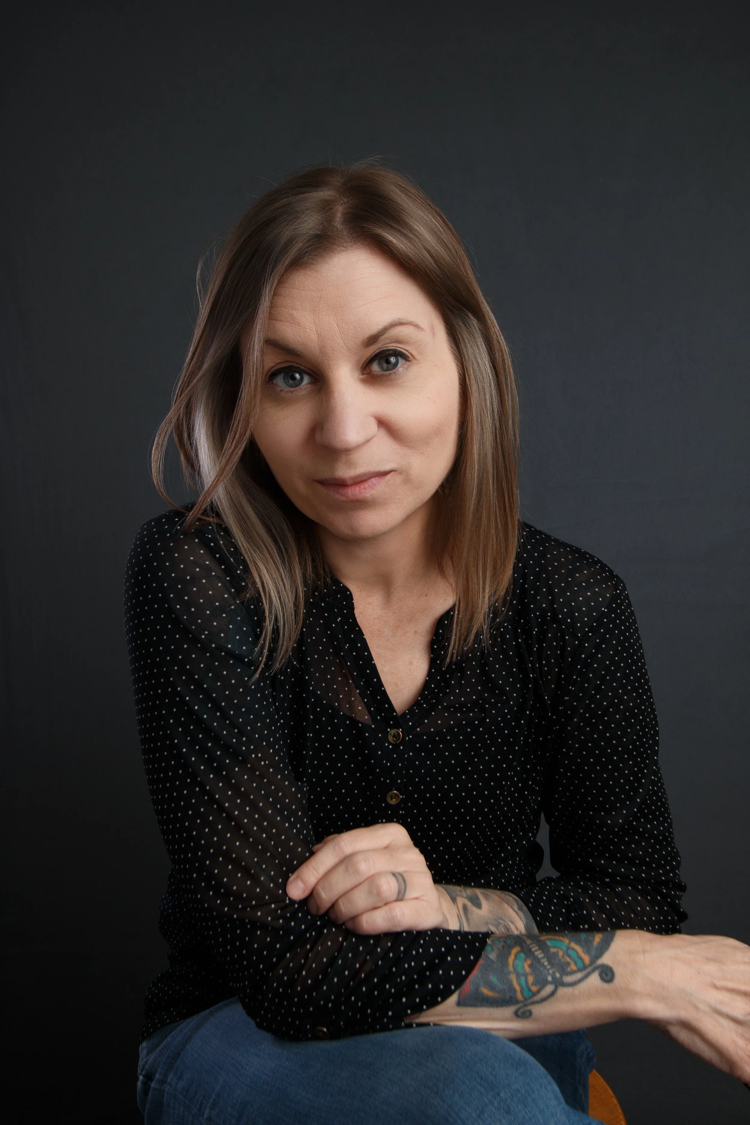 Portrait of woman in studio with dark background relaxed expression and seated pose / Photo by Erin Valkner Photography of New Braunfels, Texas. See more at www.erinvalknerphotography.com/blog