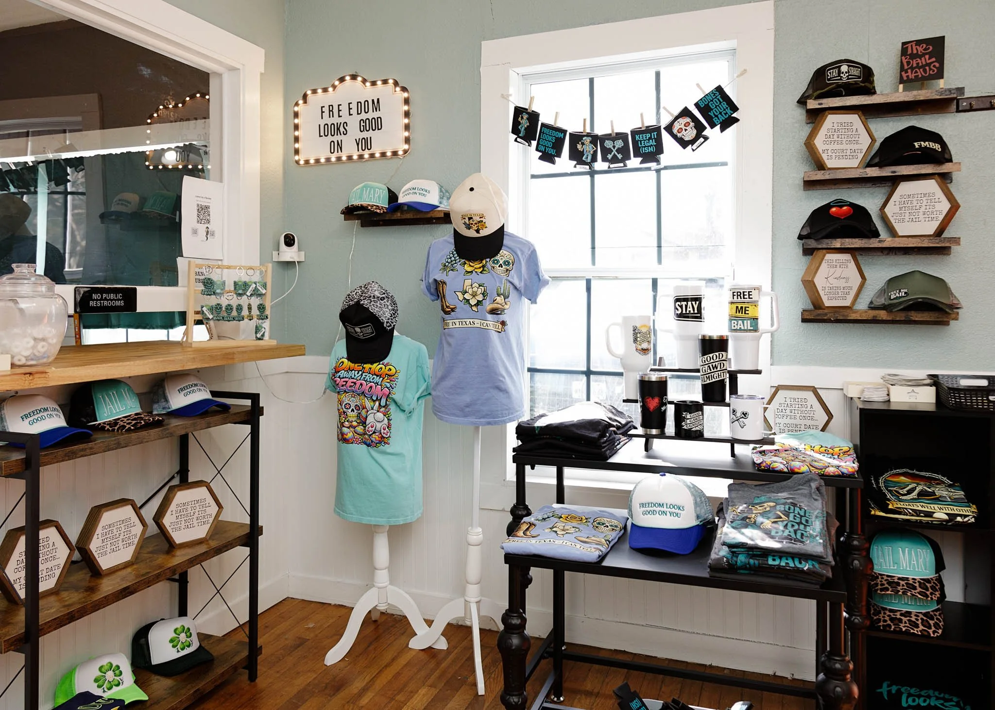 Interior photo of lobby including decor and table top displays of products hat, shirts, mugs, koozies and stickers at Free Me Bail Bonds in New Braunfels, Texas
