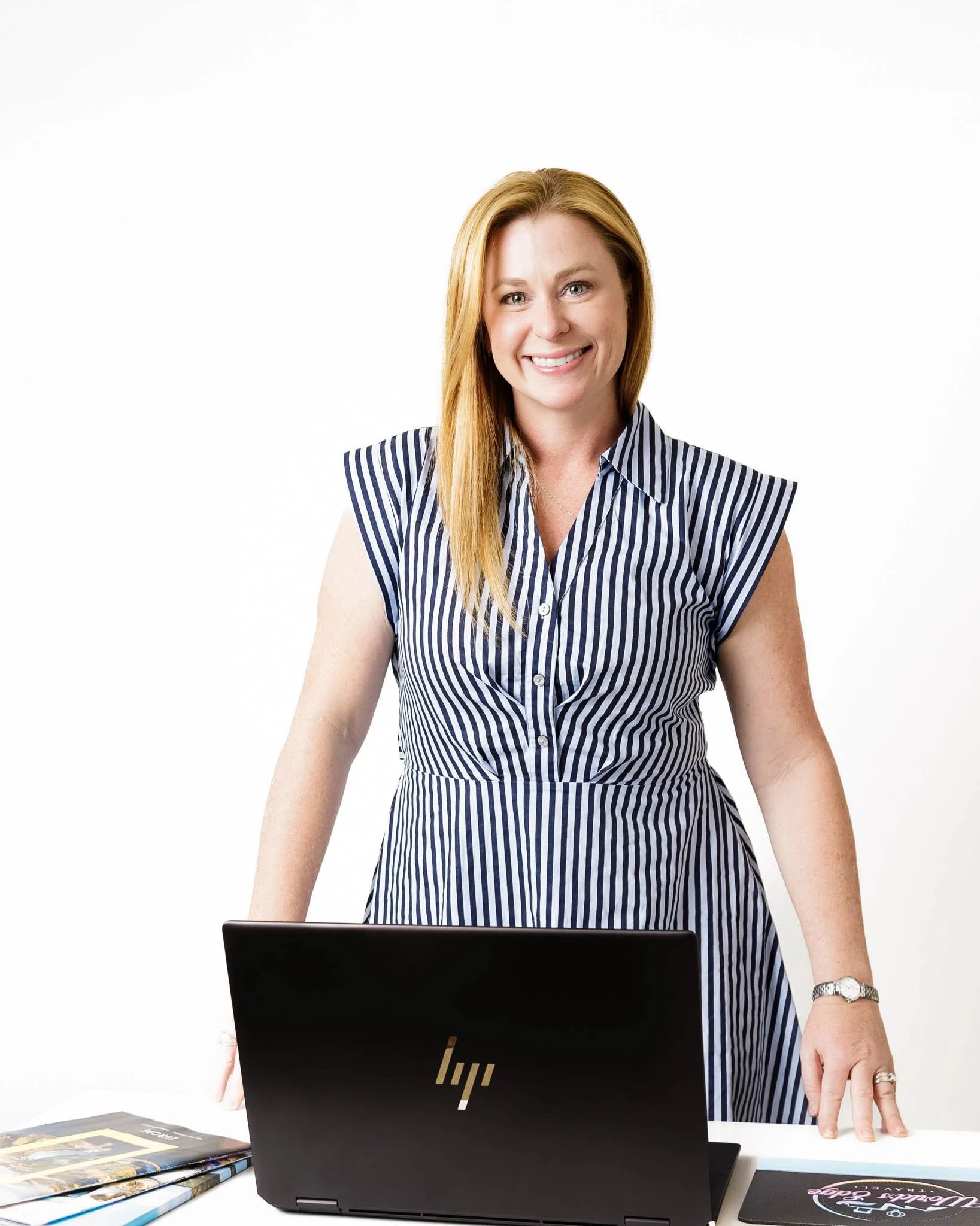 lifestyle editorial headshot of woman standing at white desk with laptop and work items on desk white background  / Photo by Erin Valkner Photography of New Braunfels, Texas. See more at www.erinvalknerphotography.com/blog
