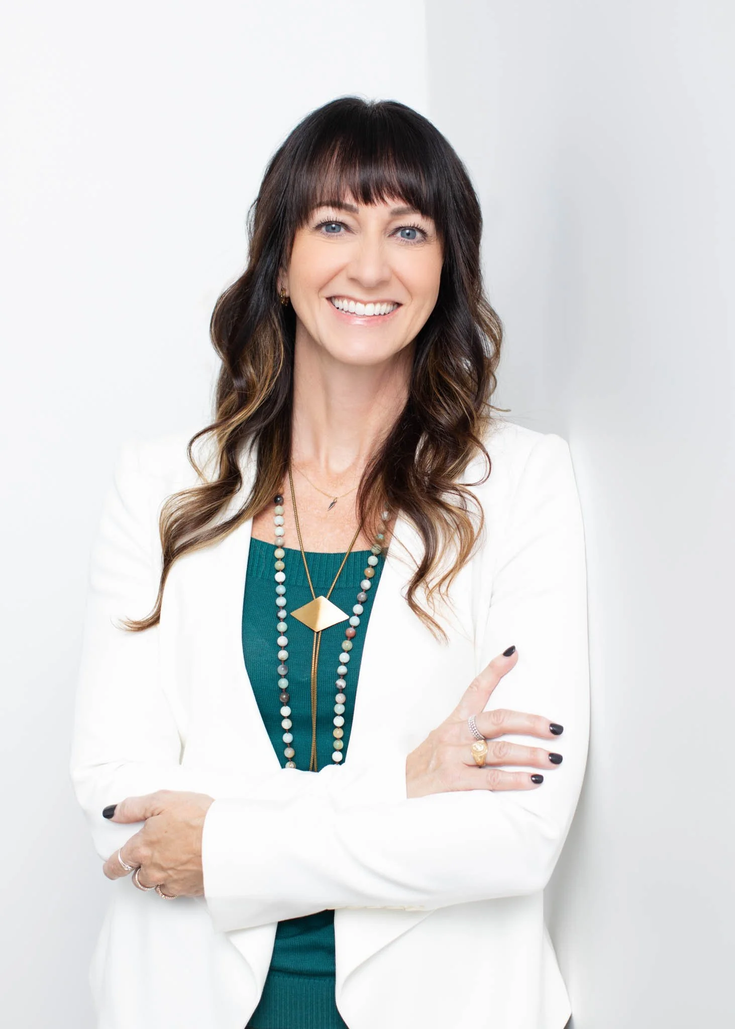 headshot branding photo of woman wearing white suit jacket with white backdrop in New Braunfels Texas studio leaning against wall | see more at erinvalknerphotography.com/blog